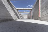 an under construction walkway in cement with red windows and bars above it with a blue sky in the background