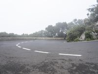 a person riding on the back of a motorcycle down a hill in an empty parking lot