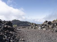 a view of the lava with clouds and trees behind it, in a mountainous area