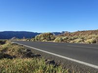 a winding mountain road next to a rocky hill and shrubs in the desert area of arizona