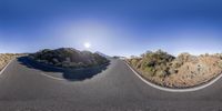 a mountain road that looks almost very sharp and wide with the sun shining bright in the sky