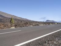 a road near the mountain side in the foggy sun day, and on the opposite bank are hills