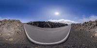 the curved road runs into a bright blue sky above some rocks on a mountain side