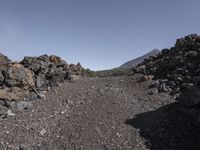 a black and gray rocky road in the middle of the desert area with rocks on either side