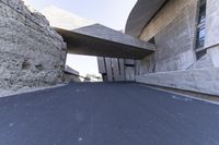 a large, concrete structure is on the side of a road in front of a stone wall