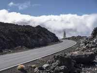 a curved road with the car on it in a barren mountain landscape with grey rock and grass