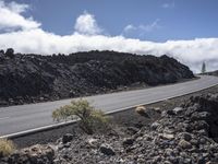 a curved road with the car on it in a barren mountain landscape with grey rock and grass