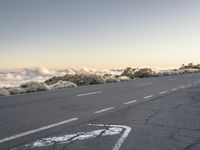 there is a sign in the middle of a empty road on top of a mountain