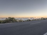 a highway passing through the hills next to the sea of clouds and trees with fog rising in the distance