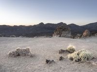 a desert landscape with some mountains in the background and a blue sky and yellow light