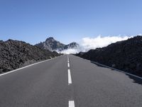 the empty road stretches into the distance at a high altitude with some clouds and steam rising out of the mountains behind