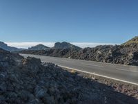 a paved highway running through an mountainous landscape with mountains in the background as seen from near the roadside