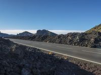 a paved highway running through an mountainous landscape with mountains in the background as seen from near the roadside