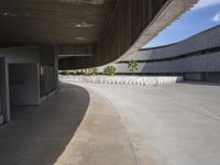 a long concrete patio leading to a parking lot with lots of doors to the side