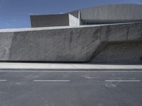 a man riding a skateboard in front of an interesting building in a parking lot