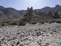 the view of a desert mountain with rocks and boulders around it and a person riding a motorcycle near the rock formation