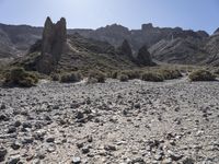 the view of a desert mountain with rocks and boulders around it and a person riding a motorcycle near the rock formation