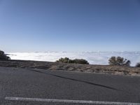 a person riding a skateboard down a slope above the clouds in the sky in a mountainous setting