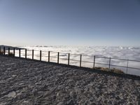 a person standing on top of a mountain looking at the clouds below her railings