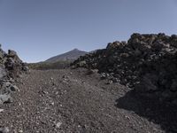 there is a very large pile of rocks at the top of a mountain as people walk up and down the hill