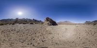 a panoramic shot of rocky mountains and deserts under a sunburste