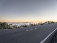 road next to clouds in the distance and sky with a cloud filled mountain in the background