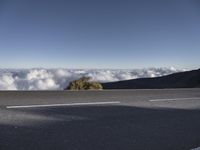 view from top of mountain with cars driving on road below clouds in the sky,