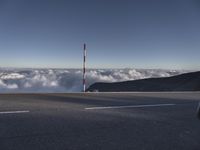 view from top of mountain with cars driving on road below clouds in the sky,