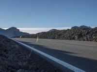 a mountain with rocks and a road next to it on a clear day with a mountain behind