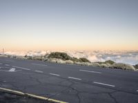 a road with an empty street sign on top of it near clouds above the horizon