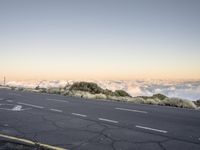 a road with an empty street sign on top of it near clouds above the horizon