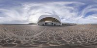 a wide angle fisheye photo taken at a stadium or stadium complex with the beach in the foreground and a small building behind it