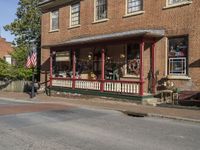 a store with a bench on the porch of it, at the corner of the street and across from a building