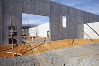 concrete wall and concrete construction material with equipment around it that is under construction and behind it is two empty cement blocks