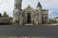 a building with two towers that appear to be made out of stones, sits on an empty lot