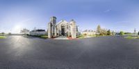 a circular panorama photo of a large, gray stone church, and street scene in the daytime with a beautiful sky