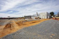 a large industrial building sitting on top of a sandy ground next to a fenced in parking lot