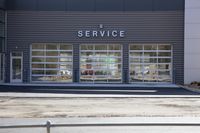 a silver street sign and windows in front of a service store, near some cars