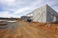 workers work at the construction site near a concrete building and pipes on a dirt ground