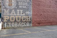 an old painted sign has been placed on the side of a building near the curb