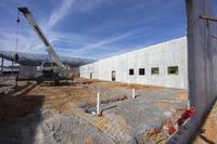 a crane is taking down something into the ground, in a building being constructed in the daytime