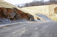 a slope on a road with gravel around it and large rocks below that show where to do work