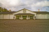 an open field front with an over sized barn on one side and a garage on the other