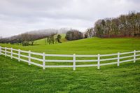 a white fence separating green grass with hills on the background in fall season in maryland usa