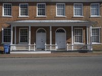 the front of a house with three white doors and a balconized porch over it