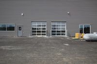 an industrial building with large windows and a grey cement ground, a yellow carton and pipes