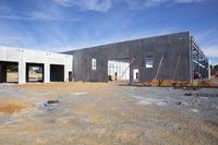 a house with concrete walls and construction materials next to a blue sky with clouds in the sky