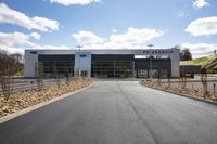 a modern ford dealership under a cloudy sky with white clouds and dirt on the floor