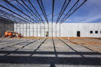 the interior of a large industrial warehouse under construction on a clear day with construction workers surrounding