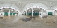 a large empty warehouse with lots of windows and cement floors, while the building is painted white